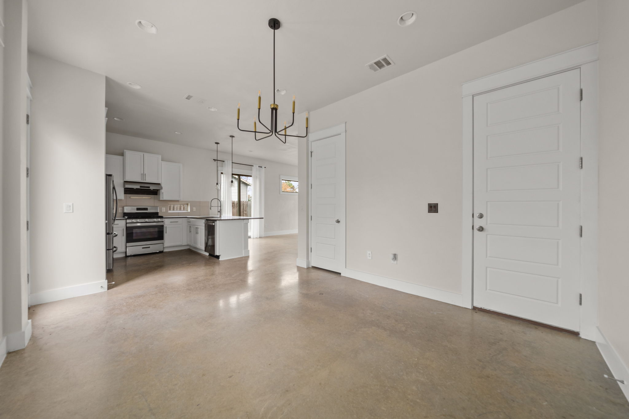 1160 Nickols Avenue, Unit A Austin, TX 78721 - Photo 37 of 40 Kitchen featuring open floor plan, stainless steel appliances, white cabinetry, decorative light fixtures, and a chandelier