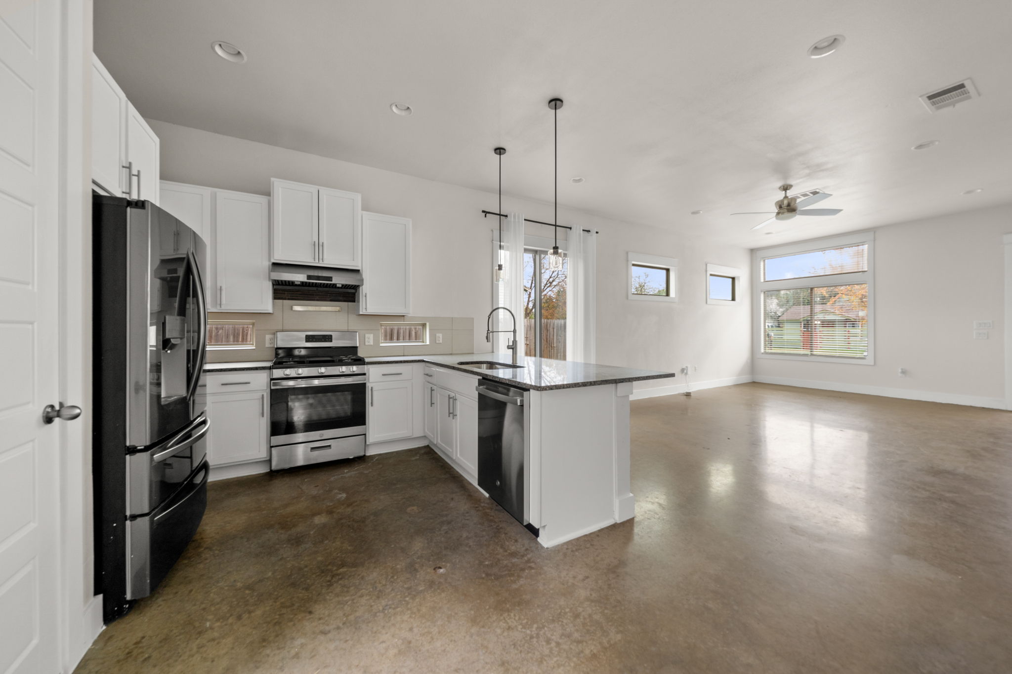 1160 Nickols Avenue, Unit A Austin, TX 78721 - Photo 39 of 40 Kitchen with finished concrete flooring, white cabinets, stainless steel appliances, open floor plan, and decorative light fixtures