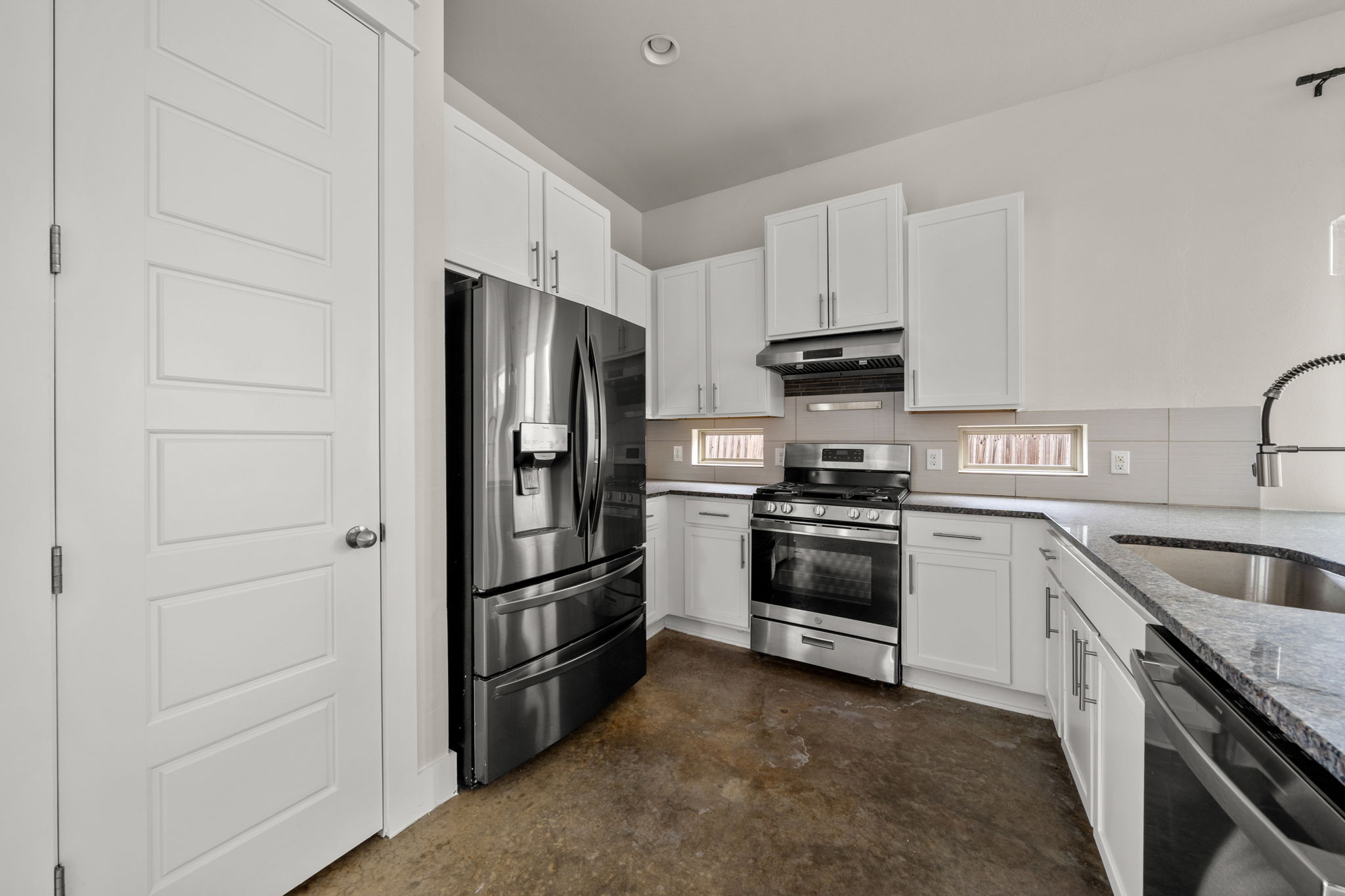 1160 Nickols Avenue, Unit A Austin, TX 78721 - Photo 4 of 40 Kitchen featuring stainless steel appliances, white cabinetry, light stone counters, concrete floors, and under cabinet range hood