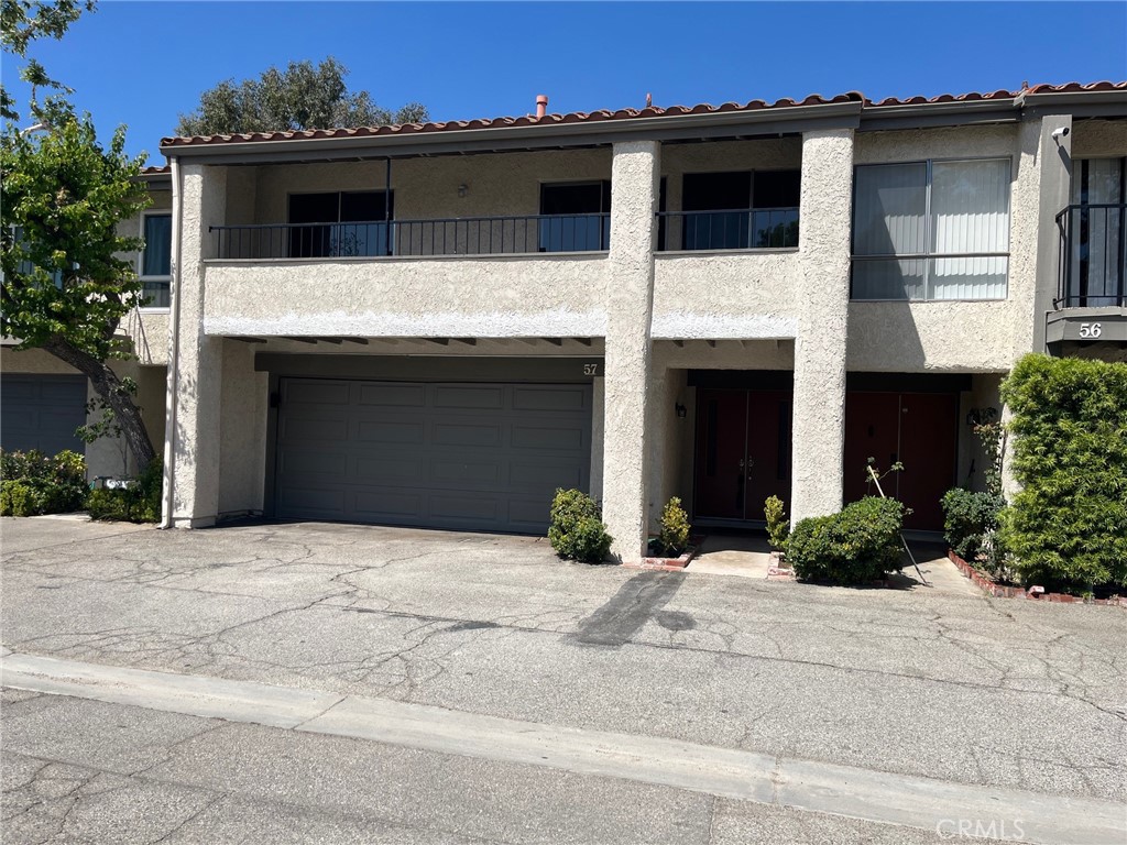 19519 Rinaldi Street, Unit 57 Porter Ranch, CA 91326 - Photo 28 of 28 a front view of a house with a yard and garage