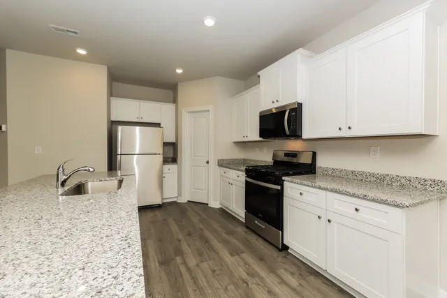 a kitchen with granite countertop white cabinets and stainless steel appliances