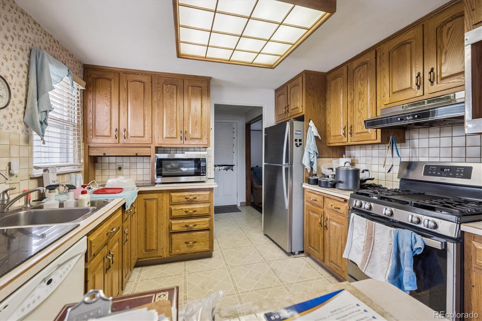5465 Reed Court Arvada, CO 80002 - Photo 11 of 27 a kitchen with a stove a sink and a refrigerator