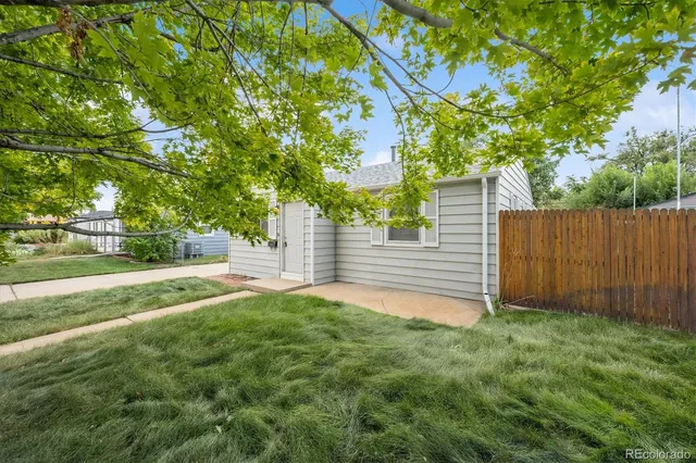 a view of a backyard with large trees and wooden fence