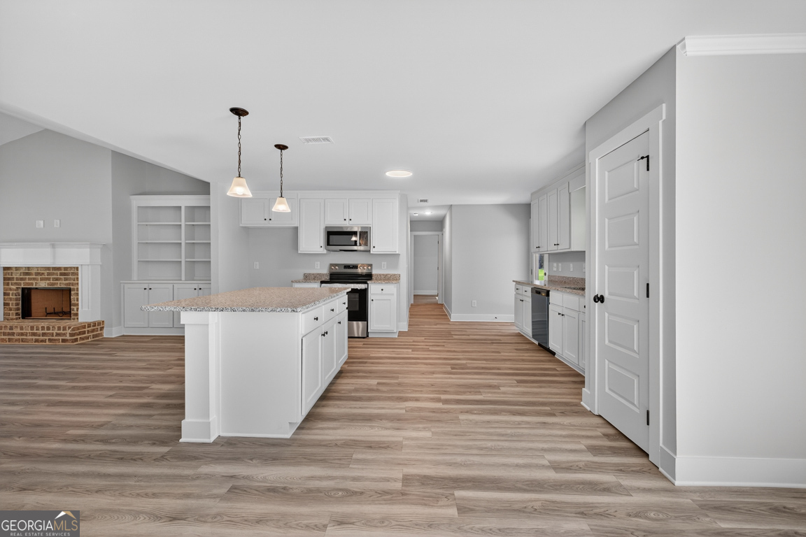 51 Brockton Way, Unit 2 Winder, GA 30680 - Photo 11 of 38 a large kitchen with a center island wooden floor stainless steel appliances and windows
