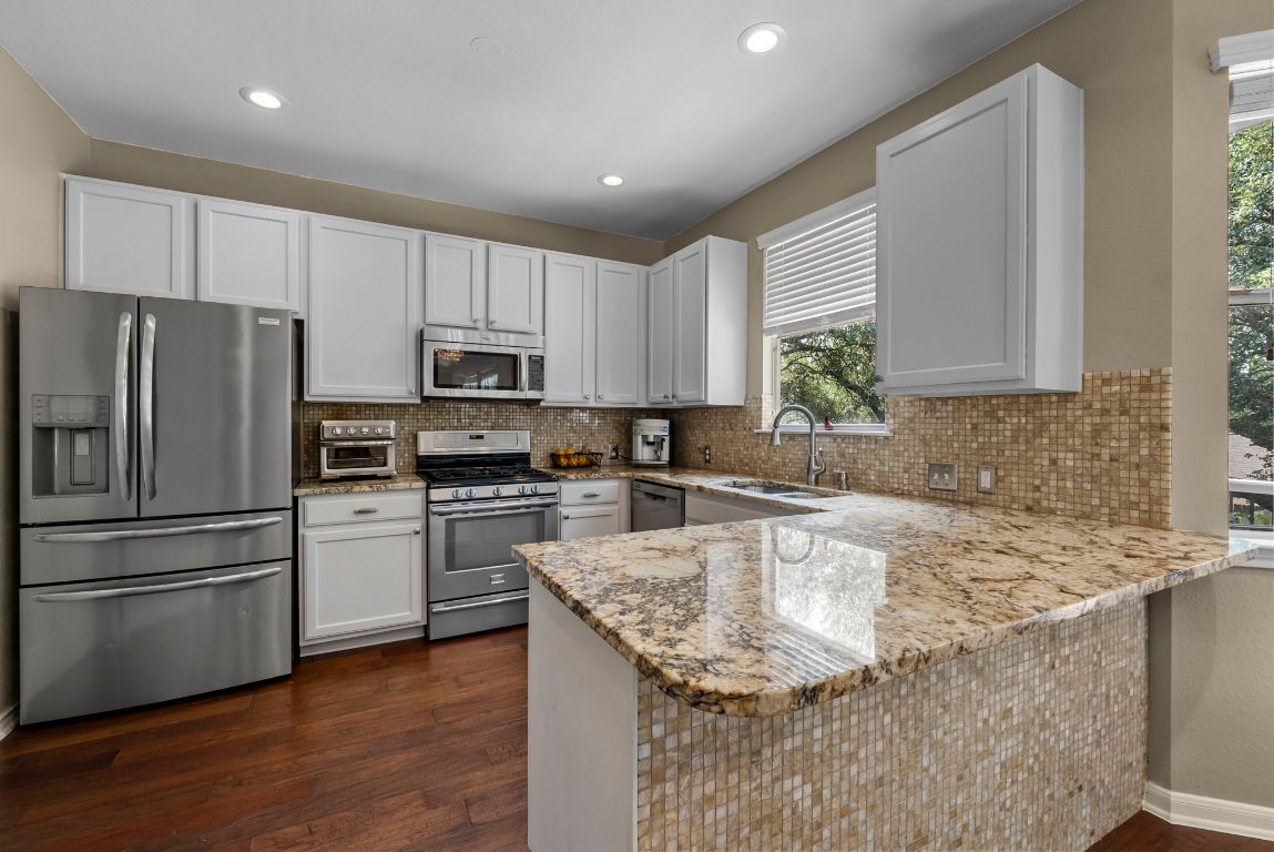 4104 Seldalia Trail Austin, TX 78732 - Photo 11 of 40 a kitchen with granite countertop stainless steel appliances a refrigerator sink and microwave