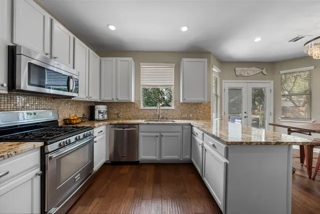 a kitchen with stainless steel appliances granite countertop wooden cabinets a sink and a stove