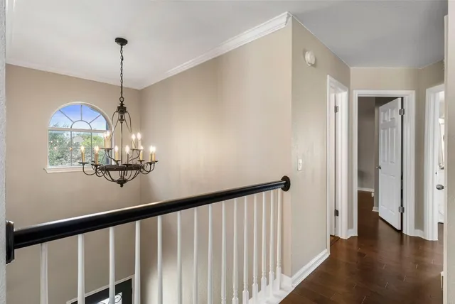 a view of a hallway to room with wooden floor and chandelier