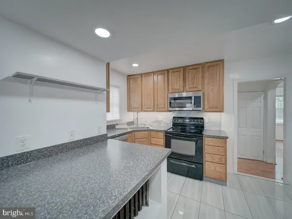 a kitchen with granite countertop a stove sink and cabinets