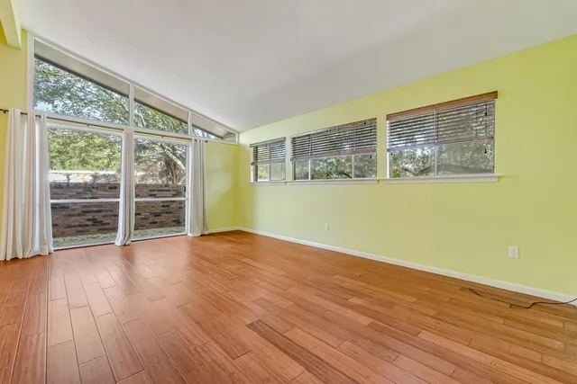a view of a big room with wooden floor a ceiling fan and windows