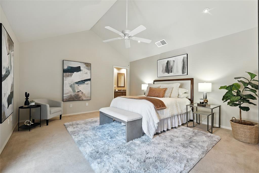 Bedroom with light carpet, ensuite bath, a ceiling fan, and high vaulted ceiling.