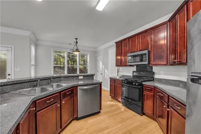 a kitchen with stainless steel appliances granite countertop wooden cabinets sink and stove top oven