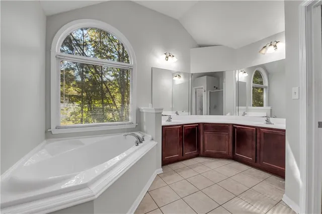 a spacious bathroom with a tub a double vanity sink a window and a mirror
