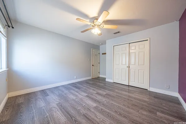 a view of an empty room with wooden floor and a window