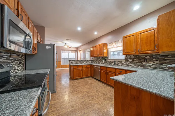 a large kitchen with stainless steel appliances granite countertop a stove a sink dishwasher and a microwave