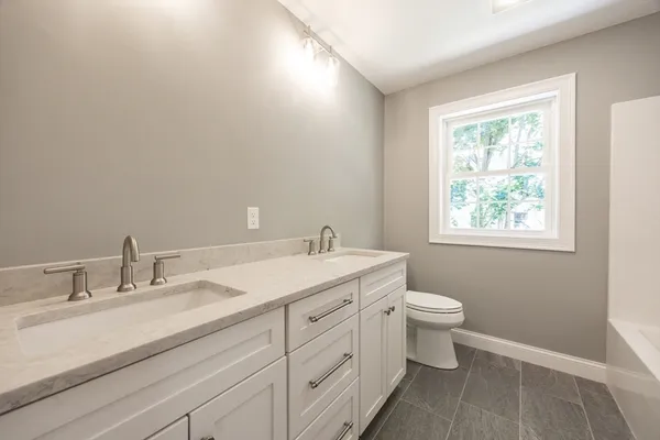 a bathroom with a granite countertop sink mirror and a toilet