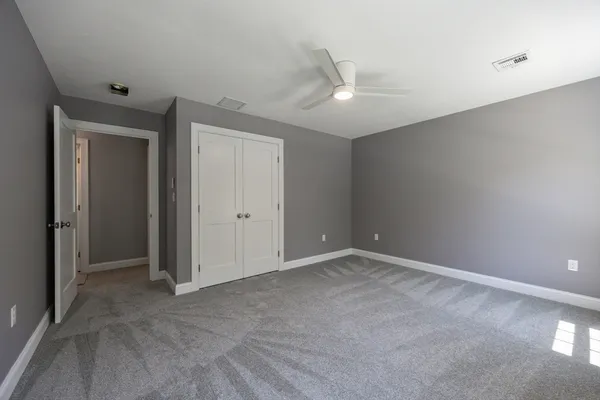 an empty room with a ceiling fan and carpet