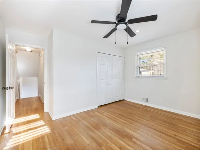 an empty room with wooden floor fan and windows