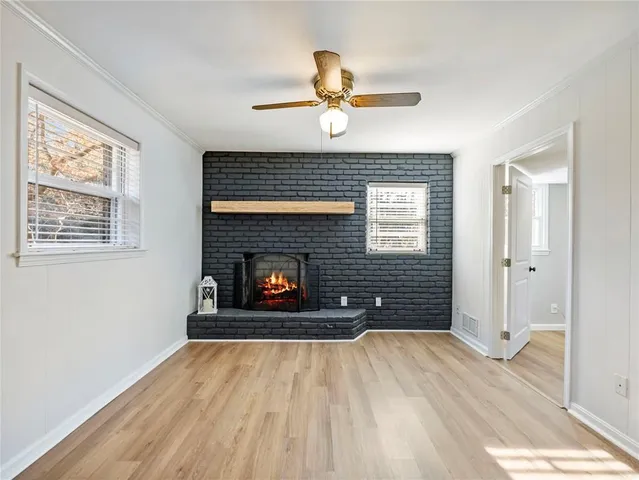 a view of an empty room with wooden floor fireplace and a window