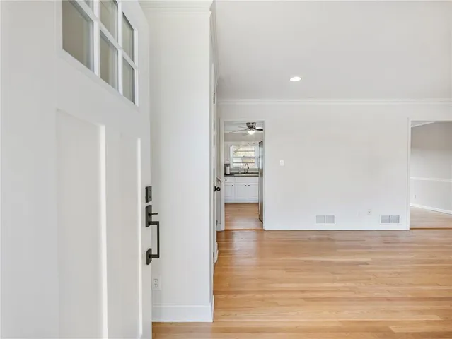 a view of an empty room with wooden floor and a kitchen