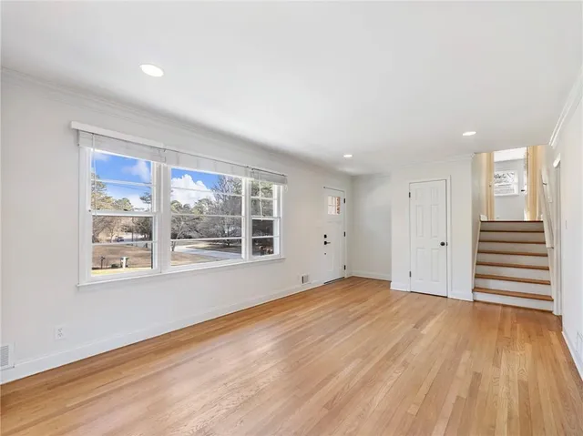 a view of an empty room with wooden floor and a window