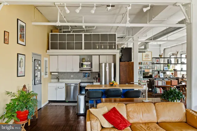 a living room with stainless steel appliances kitchen island granite countertop furniture and a potted plant