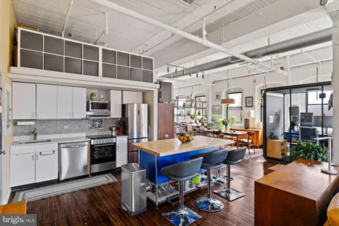 a room with stainless steel appliances kitchen island granite countertop a stove and a dining table with granite countertop wooden cabinets