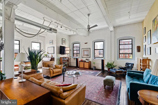 a living room with furniture a chandelier and a dining table with wooden floor