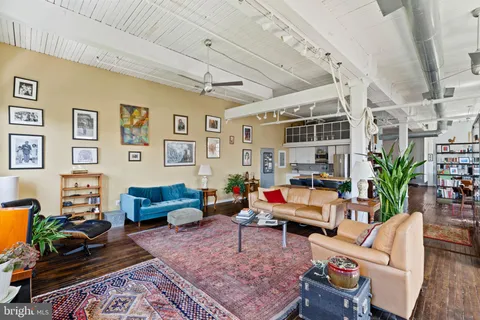 a living room with furniture kitchen view and a large window