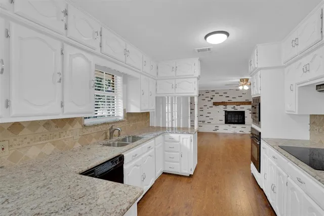 a kitchen with kitchen island granite countertop a sink cabinets and stainless steel appliances