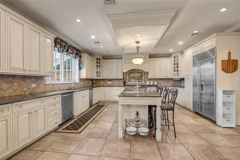 a kitchen with stainless steel appliances kitchen island granite countertop a sink a stove a table and chairs