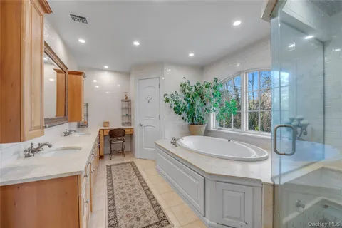 a spacious bathroom with a double vanity sink a large mirror and a bathtub