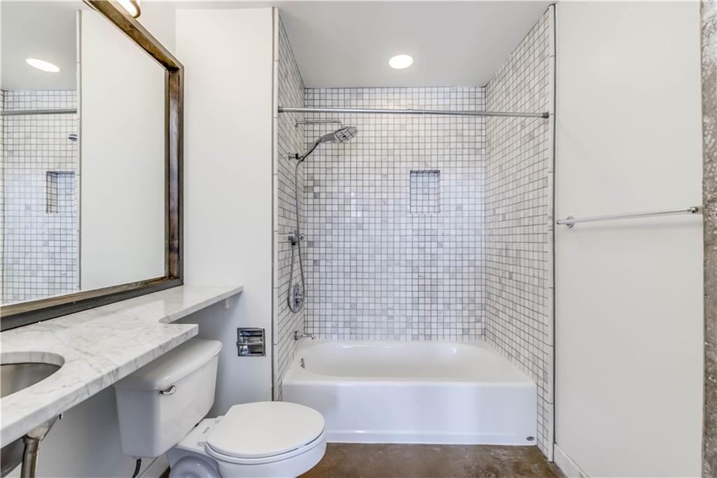 710 Colorado Street, Unit G9 Austin, TX 78701 - Photo 17 of 25 A well-appointed bathroom offers a clean aesthetic with a tiled tub/shower combination and a broad vanity.