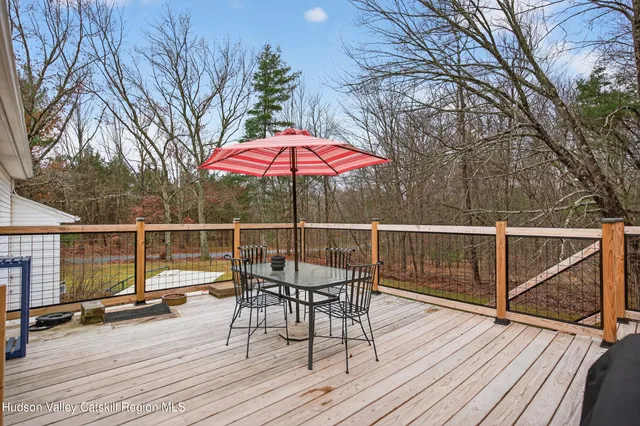 a view of a roof deck with table and chairs under an umbrella with wooden floor