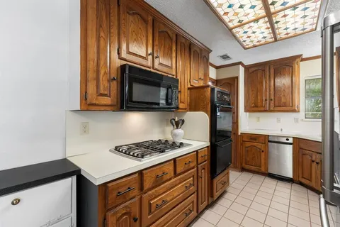 a kitchen with stainless steel appliances granite countertop a stove top oven a sink dishwasher and wooden cabinets
