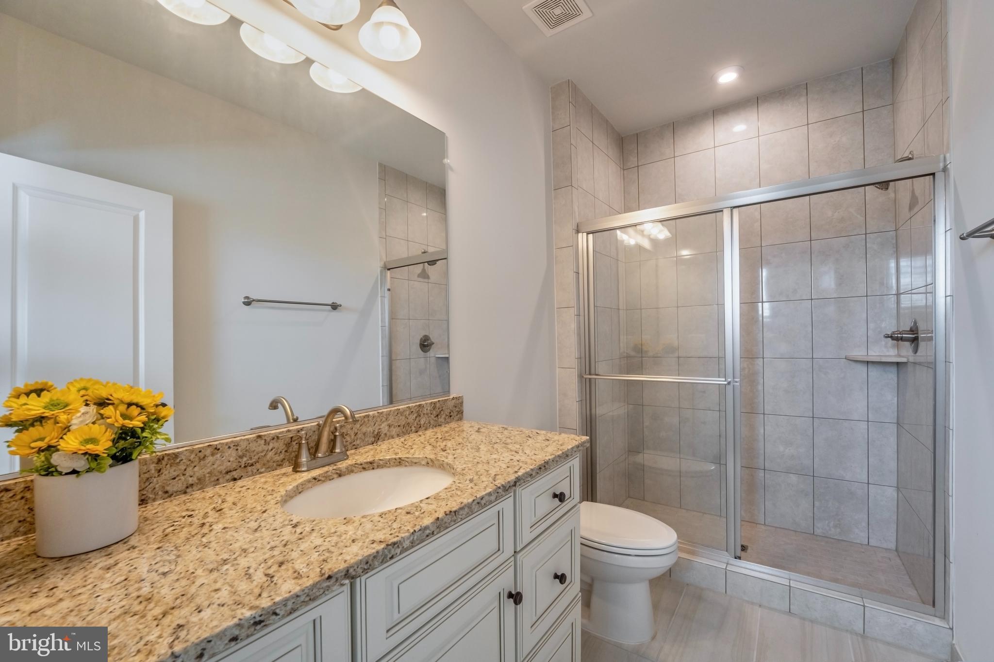 23716 September Sun Square Ashburn, VA 20148 - Photo 29 of 48 a bathroom with a granite countertop sink a toilet and shower