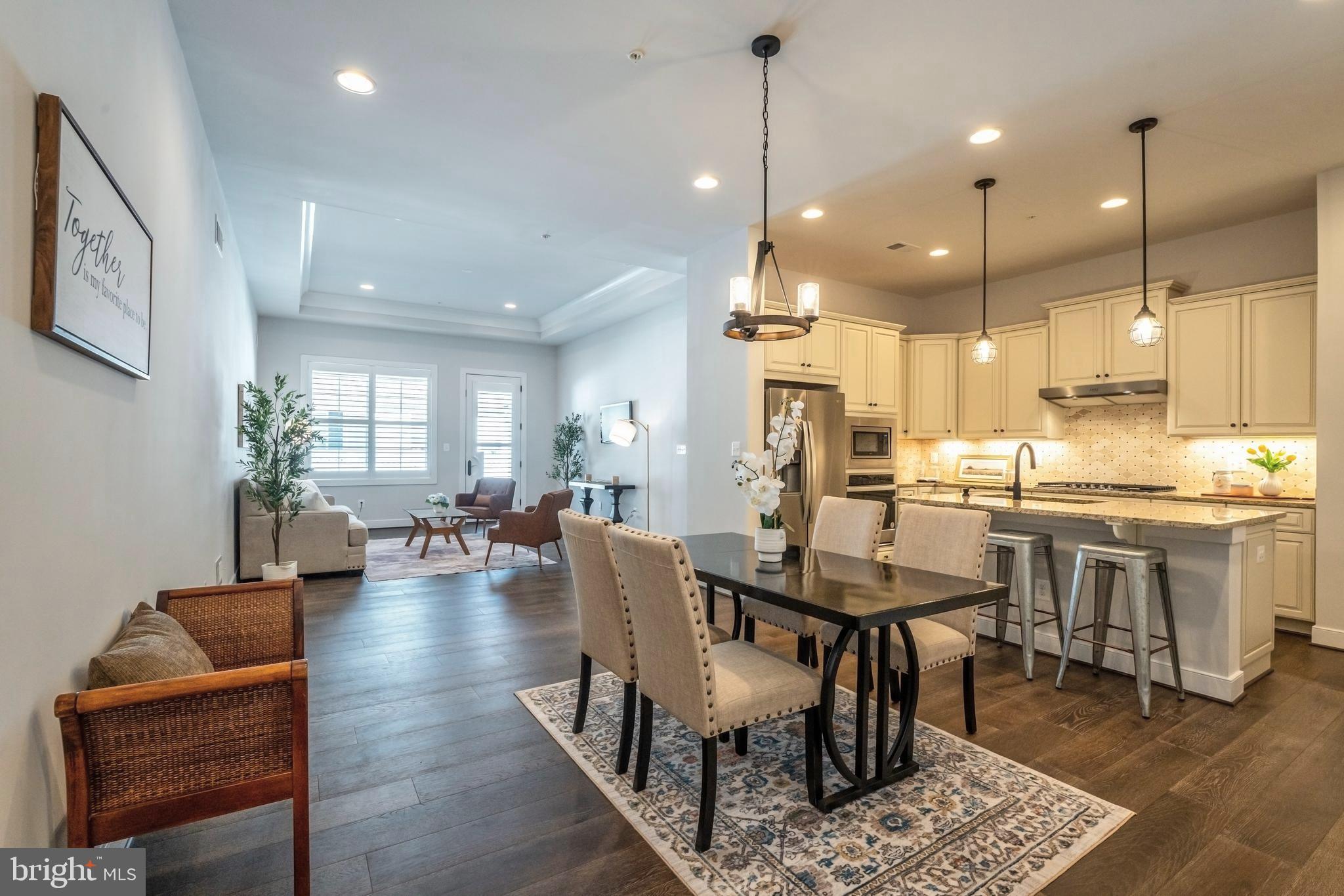 23716 September Sun Square Ashburn, VA 20148 - Photo 6 of 48 a view of a dining room and livingroom with furniture wooden floor a rug a rug a fireplace and a chandelier