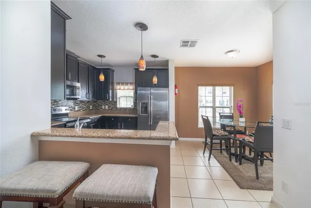 a room with stainless steel appliances kitchen island granite countertop a sink a stove and chairs