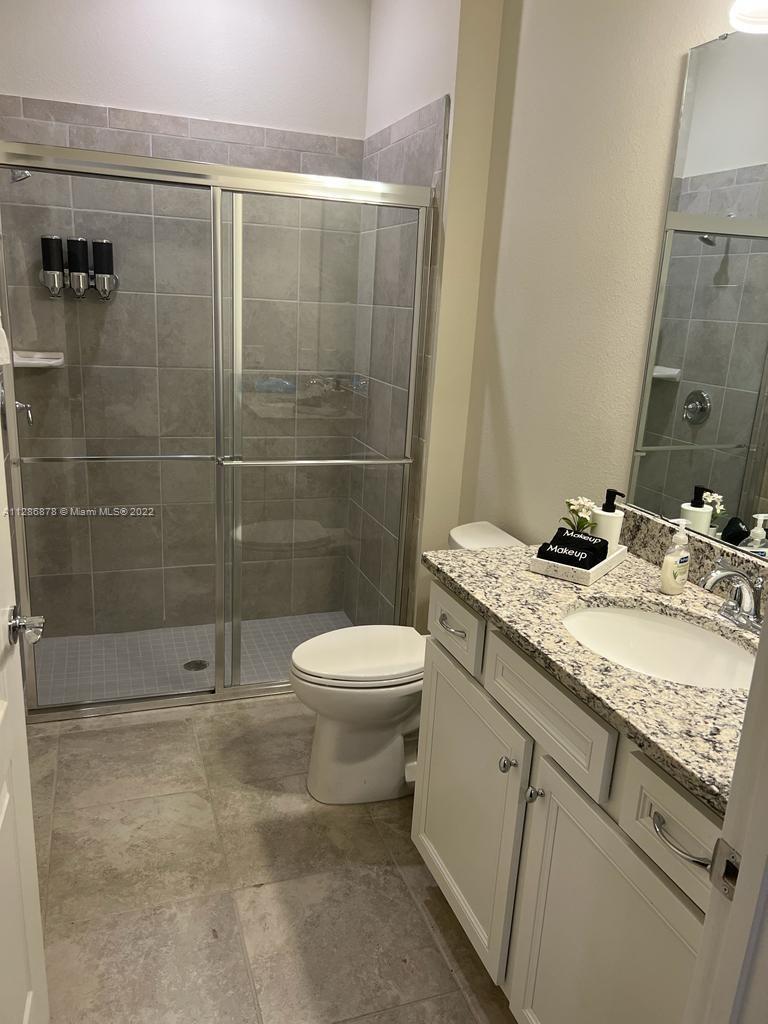 7108 Oakmoss Loop Davenport, FL 33837 - Photo 16 of 20 a bathroom with a granite countertop sink a toilet and shower
