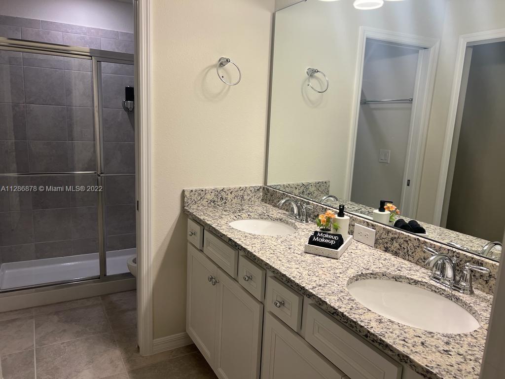 7108 Oakmoss Loop Davenport, FL 33837 - Photo 18 of 20 a bathroom with a granite countertop shower sink and mirror