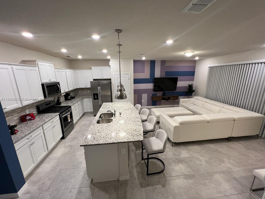 7108 Oakmoss Loop Davenport, FL 33837 - Photo 4 of 20 a living room with stainless steel appliances furniture a rug and a view