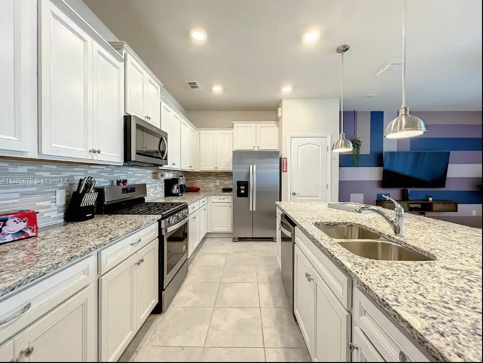7108 Oakmoss Loop Davenport, FL 33837 - Photo 7 of 20 a kitchen with granite countertop a sink stainless steel appliances and white cabinets