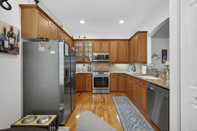 a kitchen with stainless steel appliances granite countertop a sink and wooden cabinets