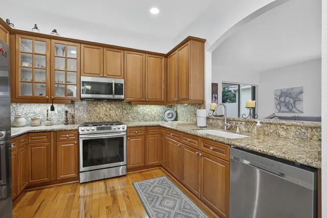 a kitchen with stainless steel appliances granite countertop a refrigerator a stove and a wooden floors