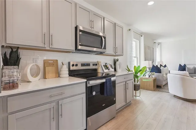a kitchen with stainless steel appliances white cabinets a sink and a stove top oven