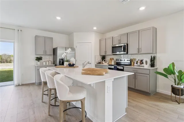 a kitchen with kitchen island a white counter top space a refrigerator cabinets and a dining table
