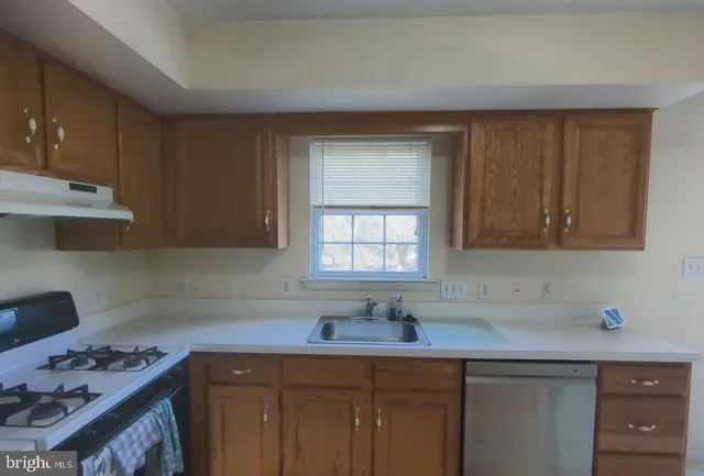 a kitchen with stainless steel appliances a sink dishwasher stove and cabinets