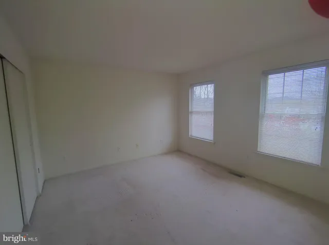 an empty room with a fan & a window