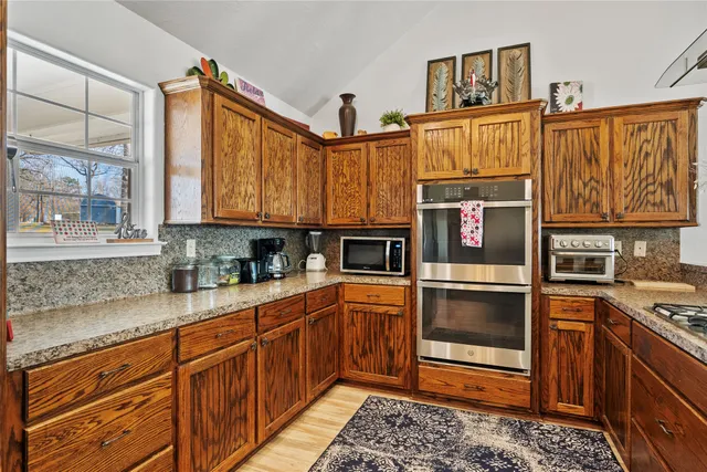 a kitchen with stainless steel appliances granite countertop a refrigerator and wooden cabinets