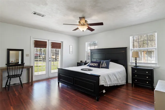 a bedroom with a bed and a large window with wooden floor