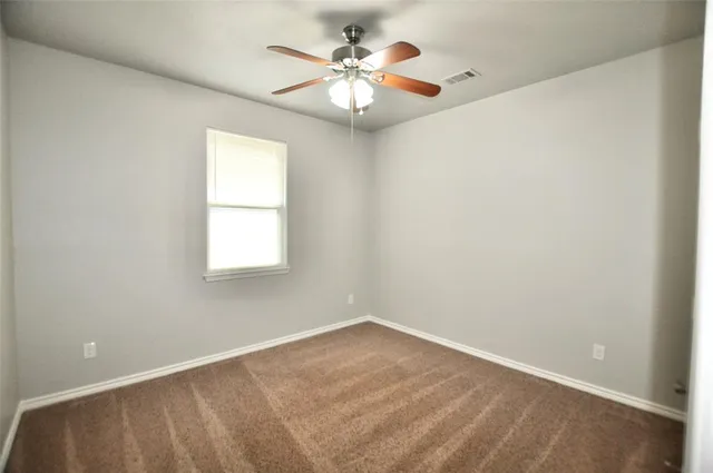 an empty room with windows and chandelier fan